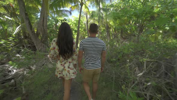 A man and woman couple walking on a path in the tropical islands in French Polynesia alt