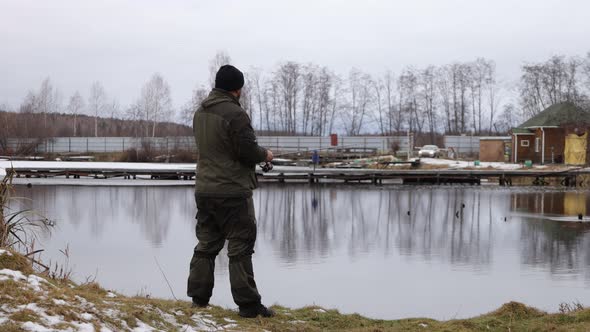 Unrecognizable Man Fishing in Lake at Dawn