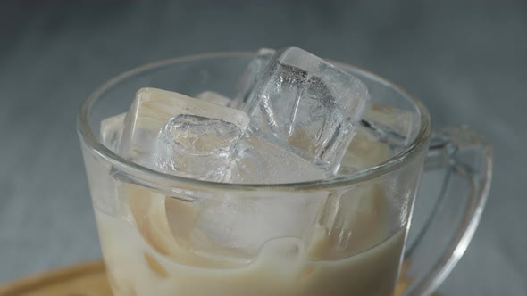 Pouring Cold Brewed Coffee over Ice. Cold coffee drink glass with ice and milk. Copy space.