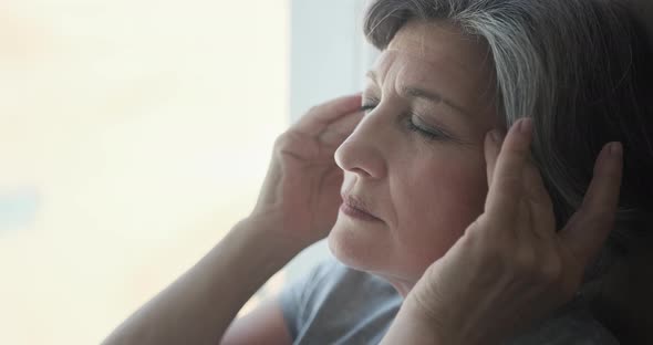 Elderly Senior Woman Massaging Her Temples to Reduce Her Headache alt