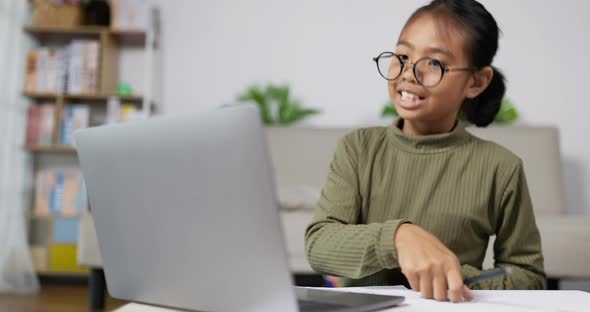 Girl kid talking and studying online with laptop in living room alt