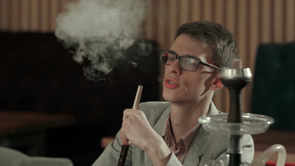 Young Man Smokes Hookah in Cafe alt
