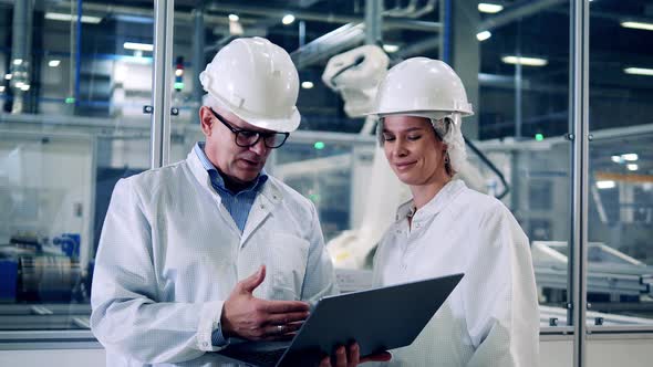 Two Plant Inspectors are Talking Near Moving Robotic Machines alt