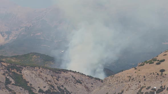 Airplane making test pass in front of wildfire burning on mountainside alt