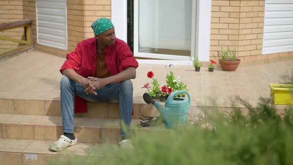 Confident Handsome Man Standing Up From Porch Taking Gardening Tools and Leaving alt