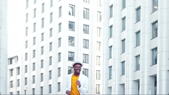 Amazed black guy in yellow t shirt and white suit dances contemporary dance alt