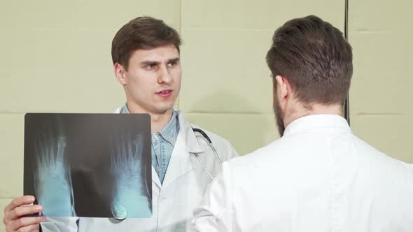 Male Doctor Discussing X-ray of a Foot with His Colleague alt