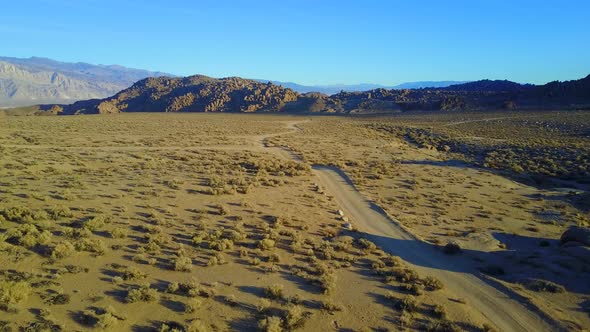 Scenic aerial drone view of dirt road and rocky desert landscape. alt