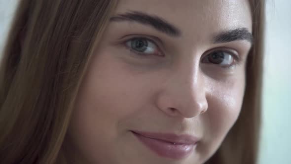 Portrait of Cute Young Woman with Different Colored Eyes Looking at Camera in the Morning alt