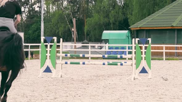 A Female Athlete Jumps on a Horse Through Obstacles in Competitions