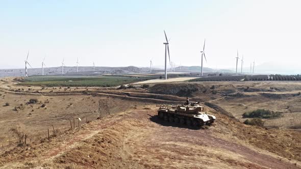 aerial view man meditating on deserted tank at wind turbine windmill farm