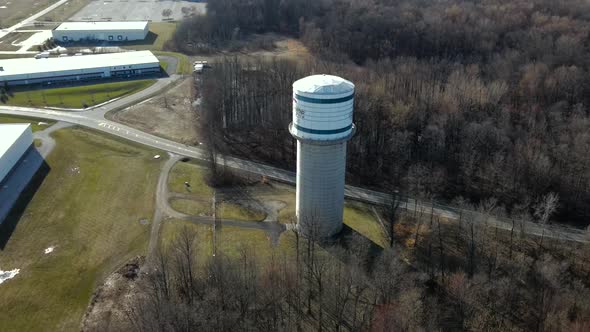 Drone shot of water tower with passing cars, on a spring day. alt