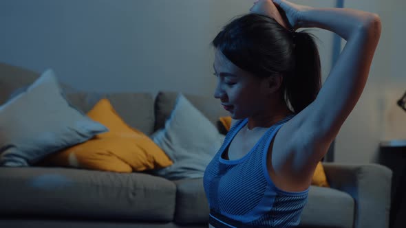 Asia lady in sportswear doing squat exercise working out in living room at home at night.