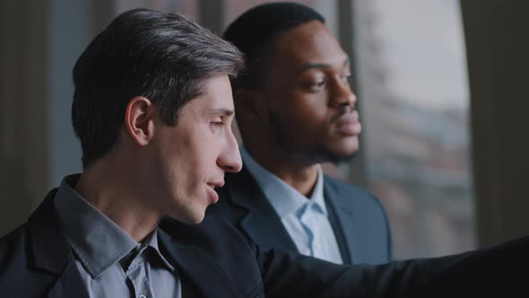 Portrait of Two Multiracial Businessmen Multinational Colleagues Looking Out Window Pointing Fingers alt