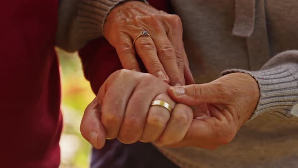 Senior Caucasian Married Couple Holding Hands Together Woman Rubs Her Husband's Hand Closeup alt