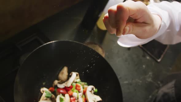 Chef adding salt on the vegetables alt
