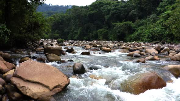 Flying very low over a mountain river full of large boulders alt