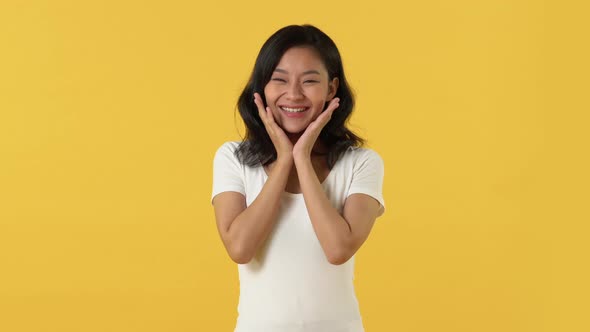 Shocked excited Asian woman with hands shaking and touching face