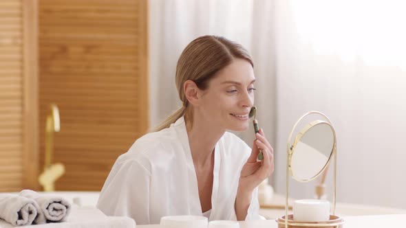 Positive Beautiful Middle Aged Woman Making Facial Skin Lifting Massage with Green Stone Massager alt
