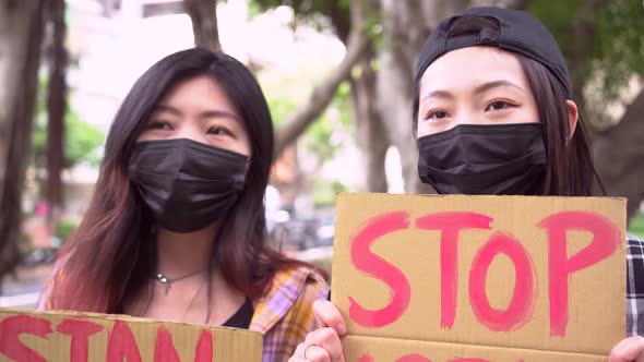 Asian women with posters during protest in city alt
