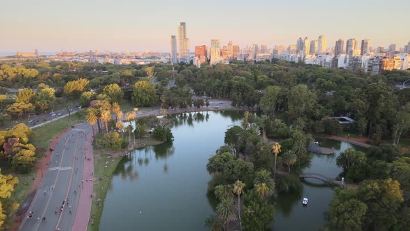 Aerial dolly out of Rosedal gardens and pond near pedestrian street in Palermo neighborhood at sunse alt