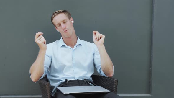 Man Sits in Chair with Laptop Listens to Music in Wireless Headphones Dancing alt