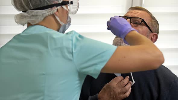 Laboratory Technician Takes Elderly Patient's Smear To Test for Coronavirus alt