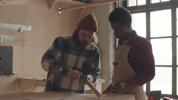 African-American Man Watching Professional Joiner Working with Wood alt