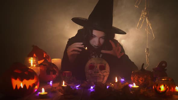 Woman in the Image of Witch is Conjuring Over the Skull with a Joss Stick and Laughing Ominously alt