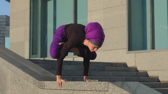 Strong Woman Yogi Girl Islamic Lady Trainer Athlete in Hijab Stands on Hands Crosses Legs in Lotus alt