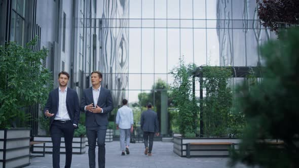 Two Successful Businessmen Walking at Modern Office Building Discussing Project alt