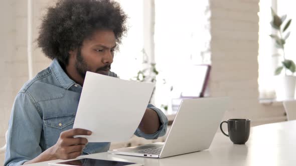 Creative African Man Doing PaperWork, Reading Documents at Work alt