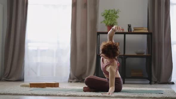 Adult Redhead Woman is Doing Exercises for Spinal at Home Practicing Yoga Training in Living Room alt