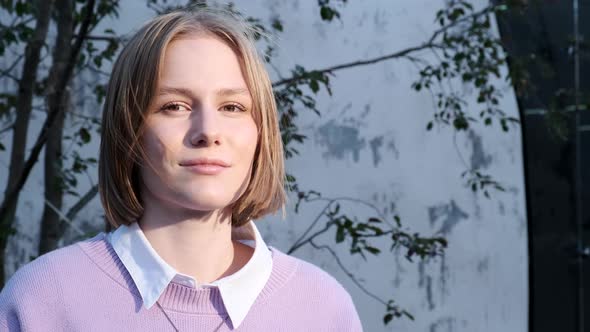 Young Woman Student with Short Fair Hair Waved By Light Wind alt