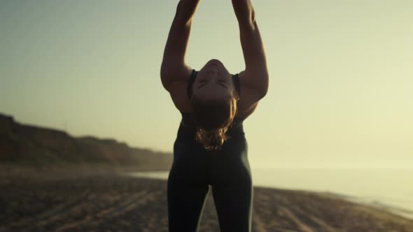 Attractive Girl Pulling Arms Back Practicing Bridge Pose at Sunset Close Up alt