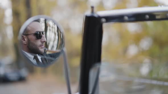 View in the Car Mirror of Handsome Driver in Sunglasses alt