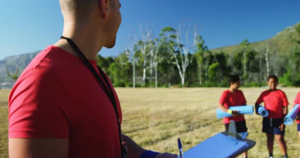 Male trainer writing on a clipboard in the boot camp 4k