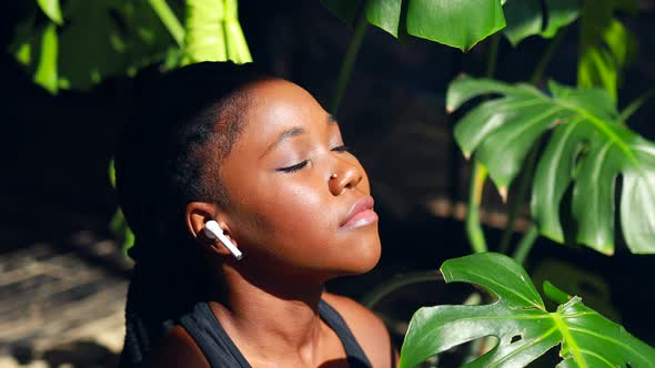 African American Woman in Black Sporty Bra is Sitting Lotus Pose on Yoga Mat Floor Closed Eyes and alt