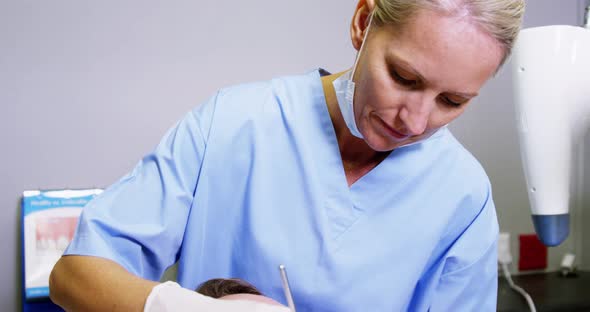 Dentist examining a male patient with dental tools alt