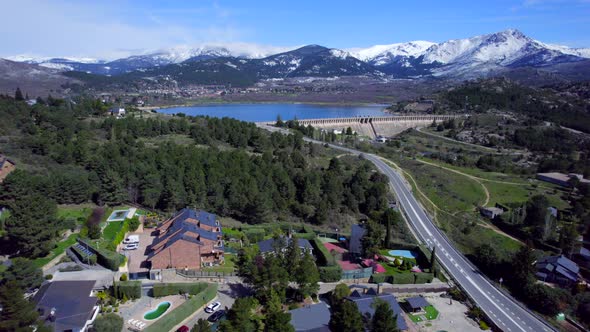 Smooth cinematic push in aerial over the town of Navacerrada towards the reservoir and the snow-capp alt