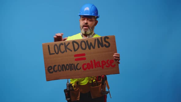 Senior Man Builder in Hardhat Holding Cardboard Placard Striking Against Blue Background