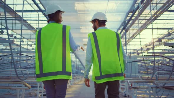 Empty Manufacture Workers Walking Among Glasshouse Devices Wearing Green Uniform alt