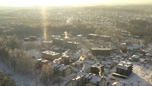 AERIAL: Flying Over Buildings During Cold Winter Day with Snowstorm Visible in Horizon