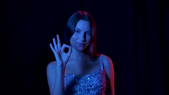 Portrait of Charming Young Woman Is Looking at Camera Smiling Shows Ok Gesture. Close Up. Slow alt