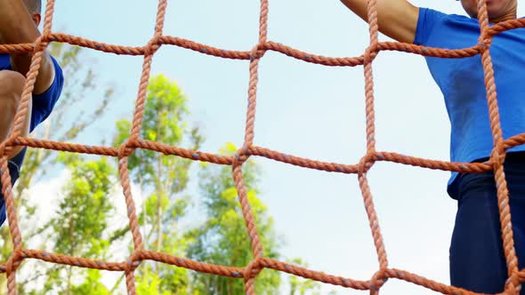 Fit man climbing a net during obstacle course 4k alt