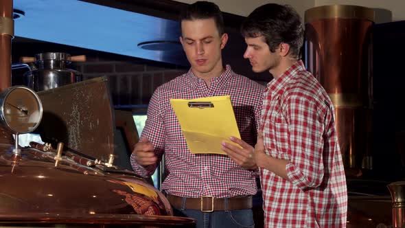 Male Brewer and His Co-worker Examining Brewing Machine at Beer Production alt