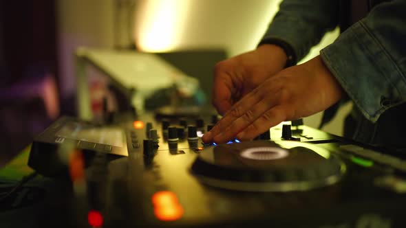 Side View of the DJ's Hands on the Remote Control to Adjust the Volume