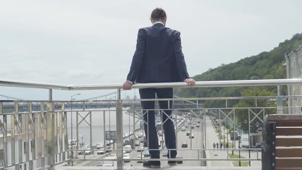 Back View Wide Shot of Suicidal Man Attempting To Commit Suicide Standing at Bridge Fence with Cars alt