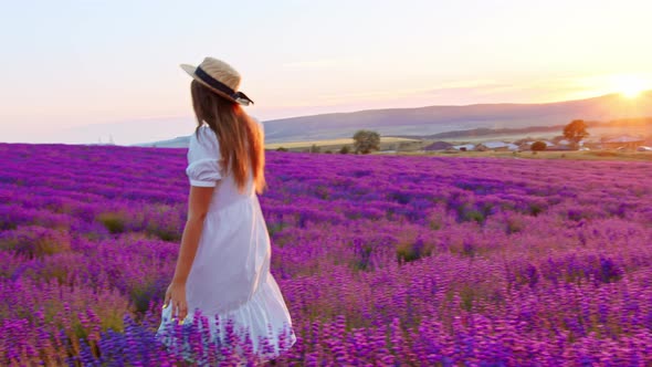 Young Woman in White Dress Walking Through a Lavender Field on Sunset