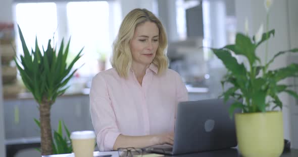 Blond woman working on laptop sitting at desk